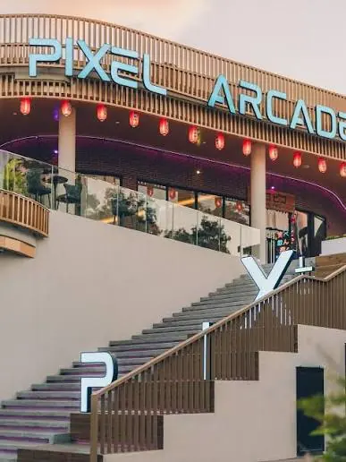 The exterior of the Pixel arcade building, with its sign lit at dusk.